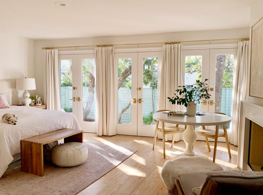 Bedroom with wall to wall french doors with curtains and round table