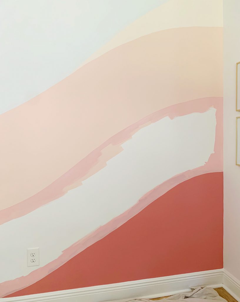Crisp edges of pink paint between two colors on abstract wall mural