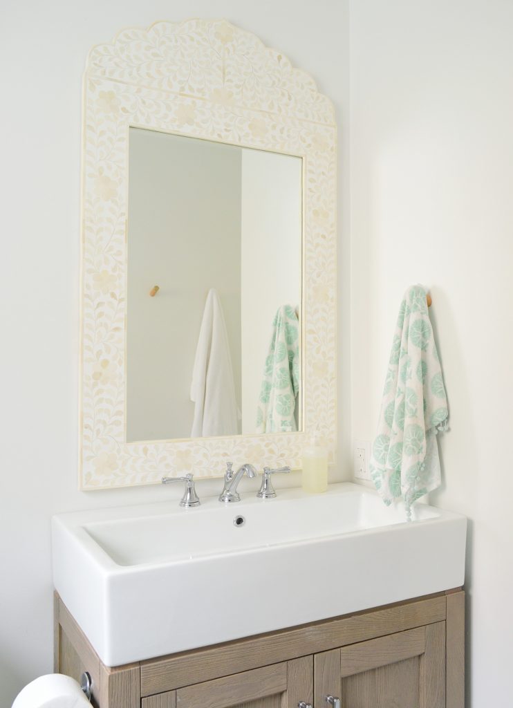 White bathroom with large capiz mirror over vanity sink