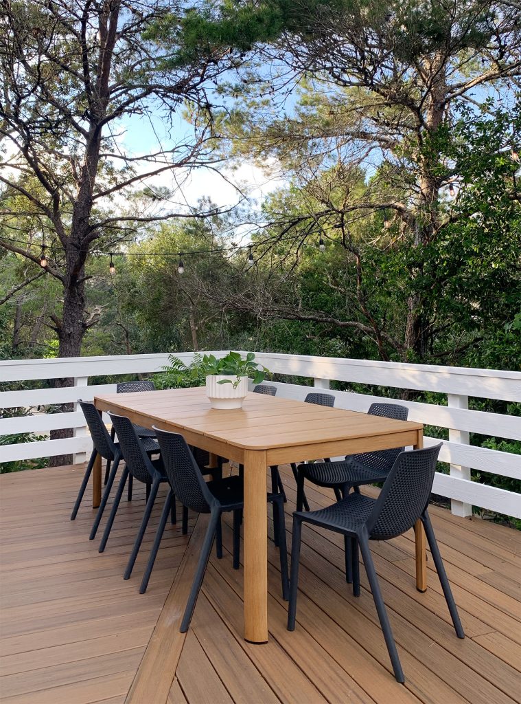 Faux Wood Metal Outdoor Dining Table With Black Chairs Surrounded By Trees