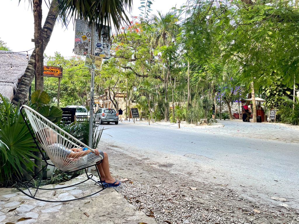 Kid sitting in rocking chair near road in Tulum Mexico