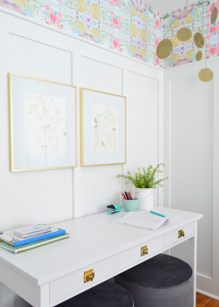 White Desk With Gold Hardware Against Board And Batten With Brass Frames And Mobile