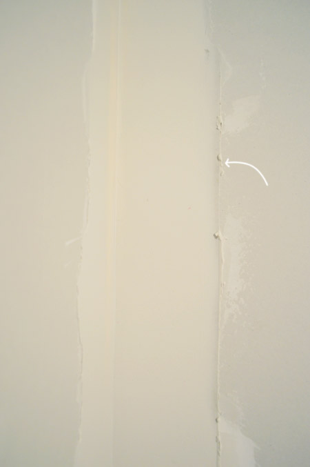 arrow pointing to ridge in drywall mud after scraping excess