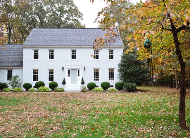 white painted brick house with fall leave and tranquility blue door