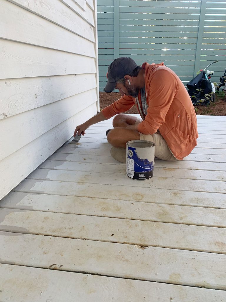 John edging porch floor with gray floor paint on paintbrush 