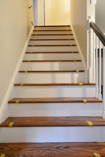 taping off placement of stair runner on wooden staircase