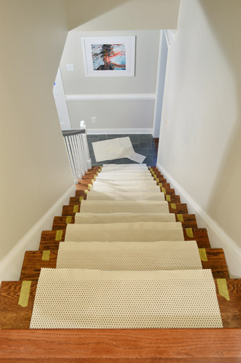 sections of rug pad placed on each step of staircase before runner